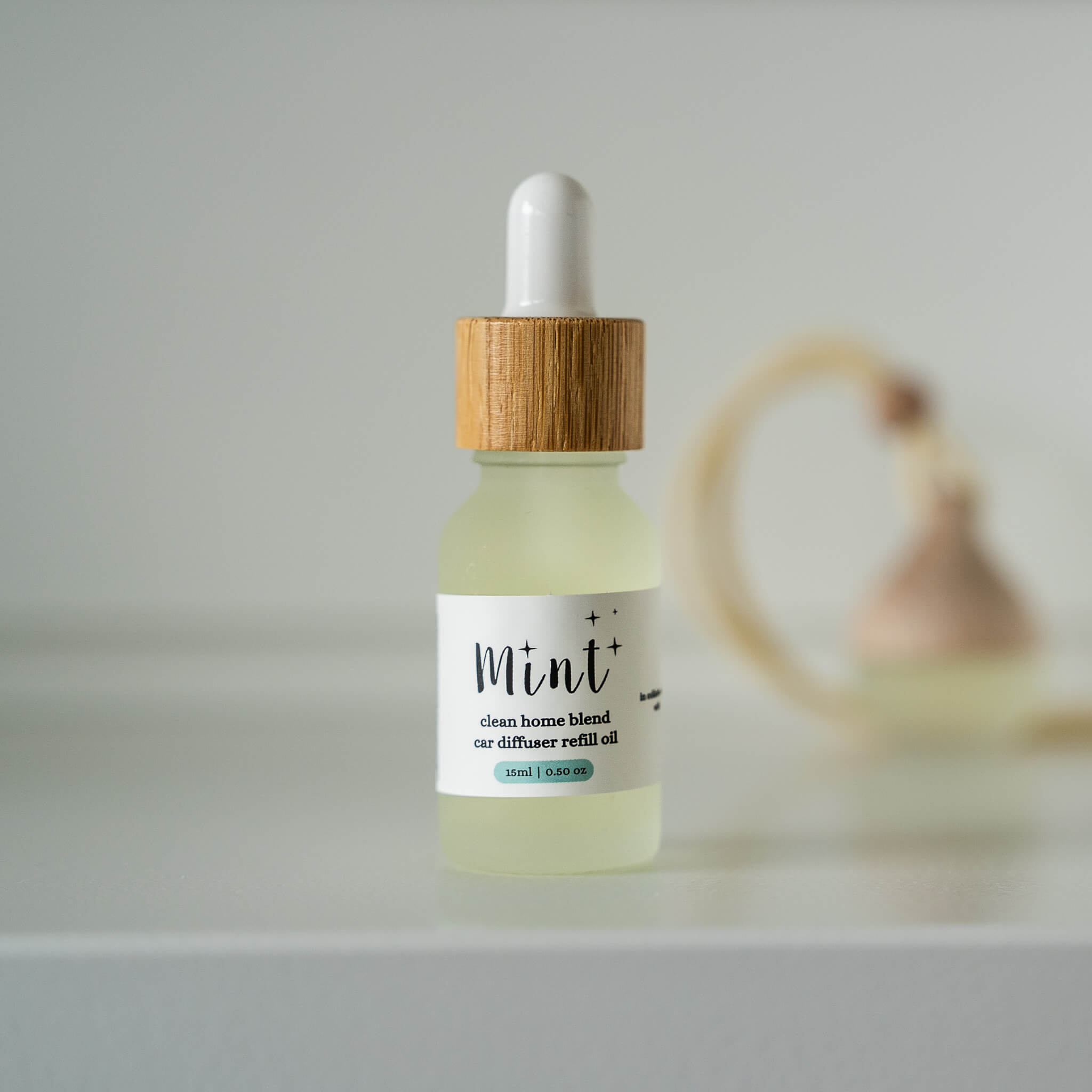 Bottle of Mint car diffuser refill oil with wooden dropper on a light gray background