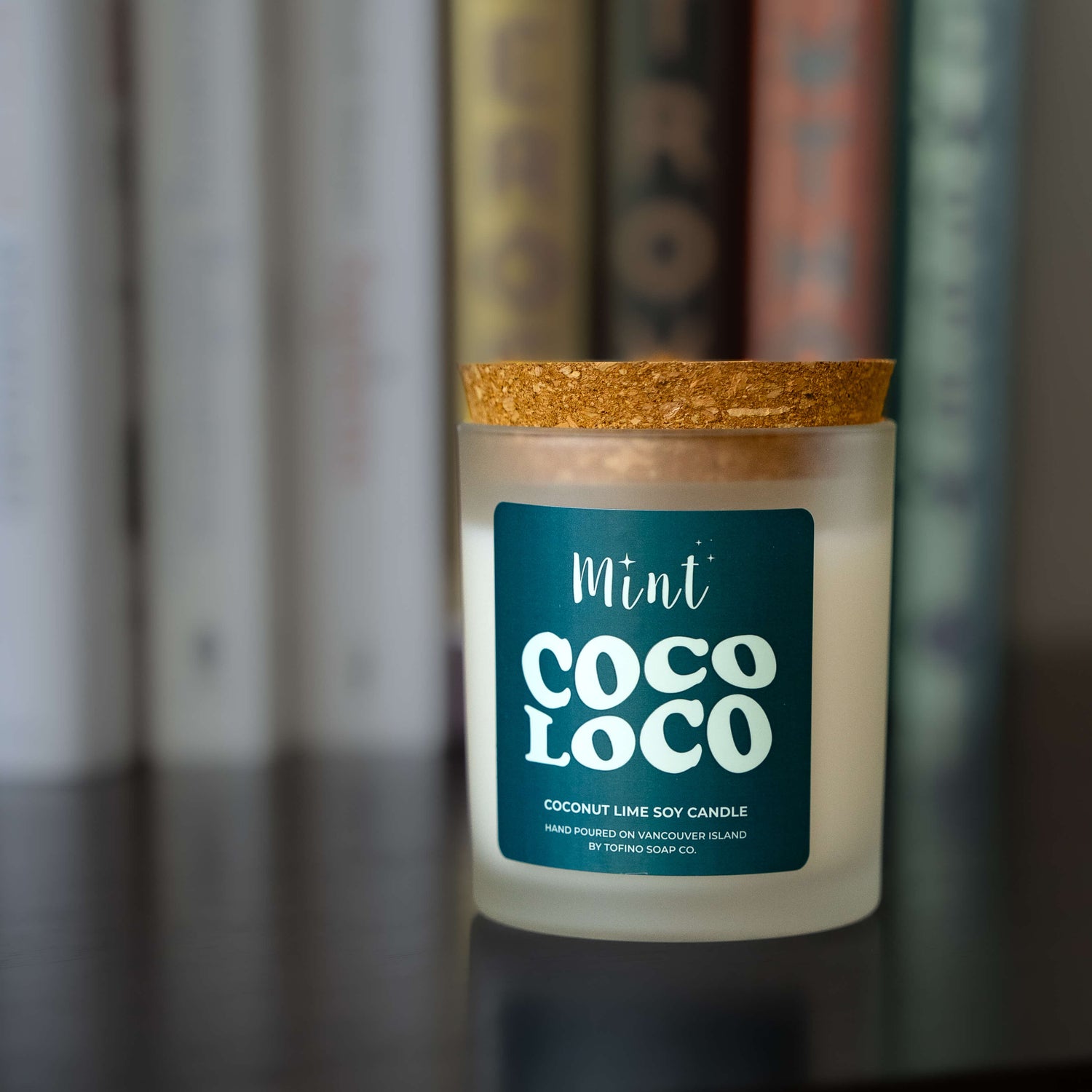 Candle with a blue label in front of books