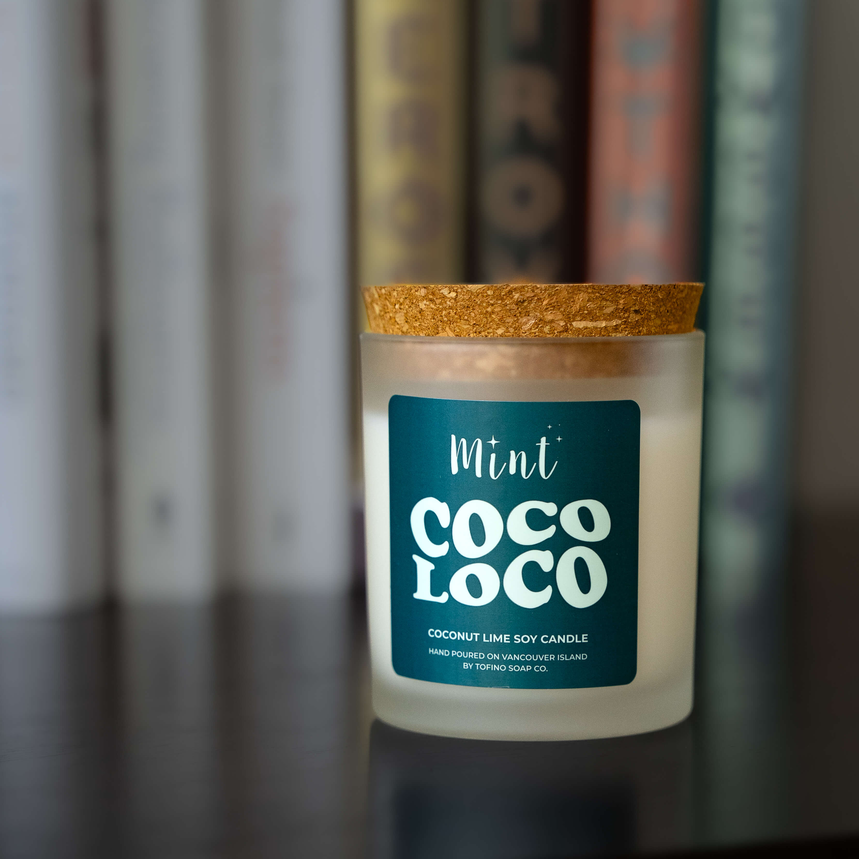 Candle with a blue label in front of books