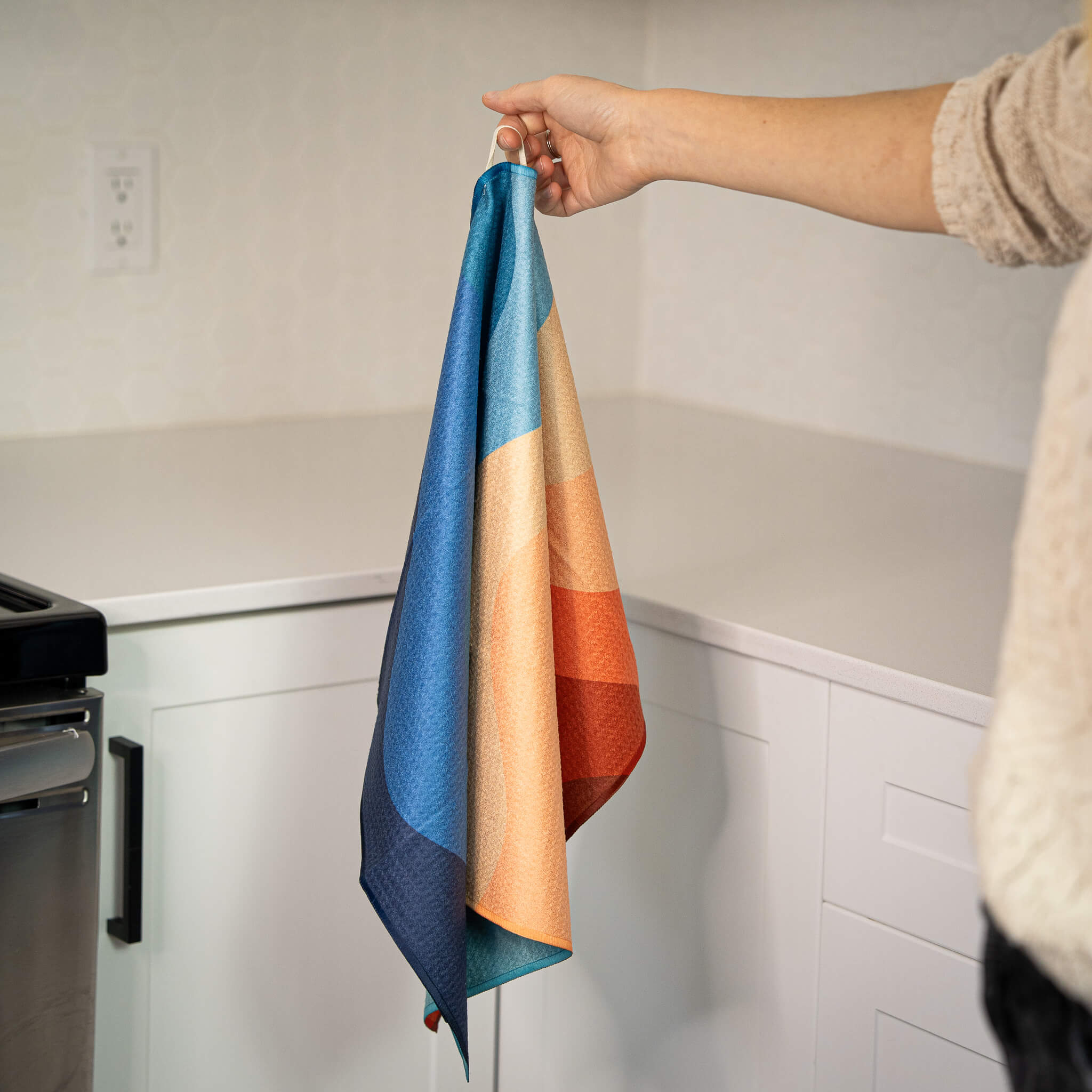 Colorful striped towel held by a person in a kitchen setting