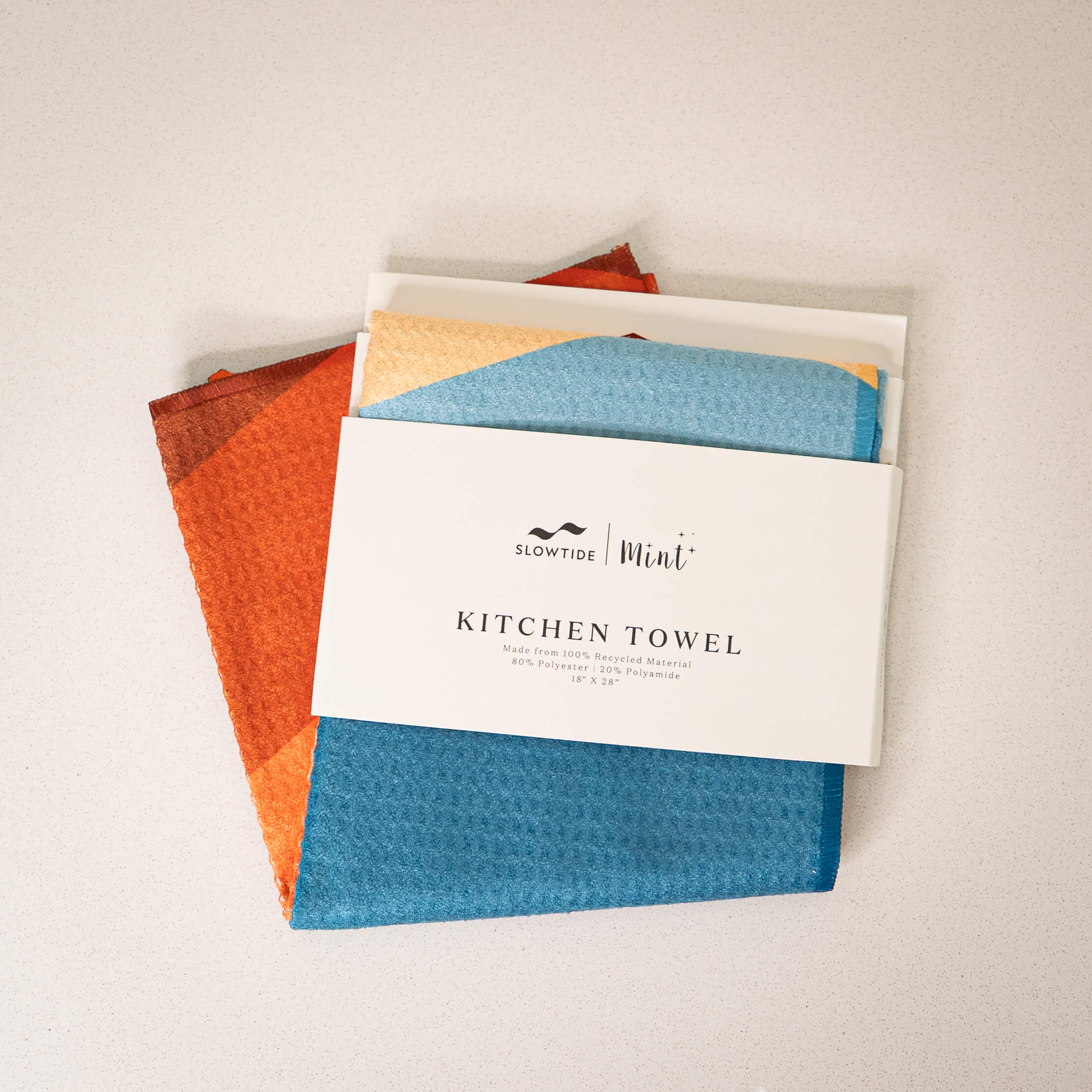 Set of colorful kitchen towels with a brand label on a light background