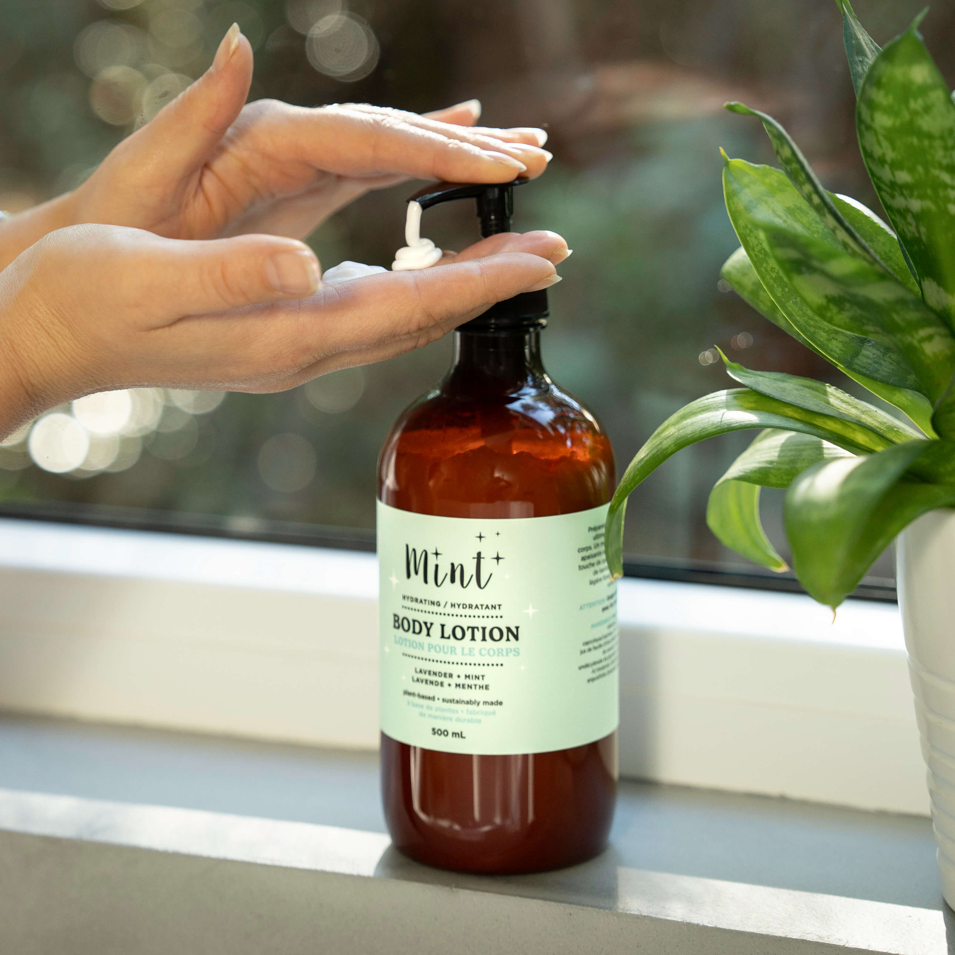 Hand holding a bottle of Mint body lotion with a blurred background
