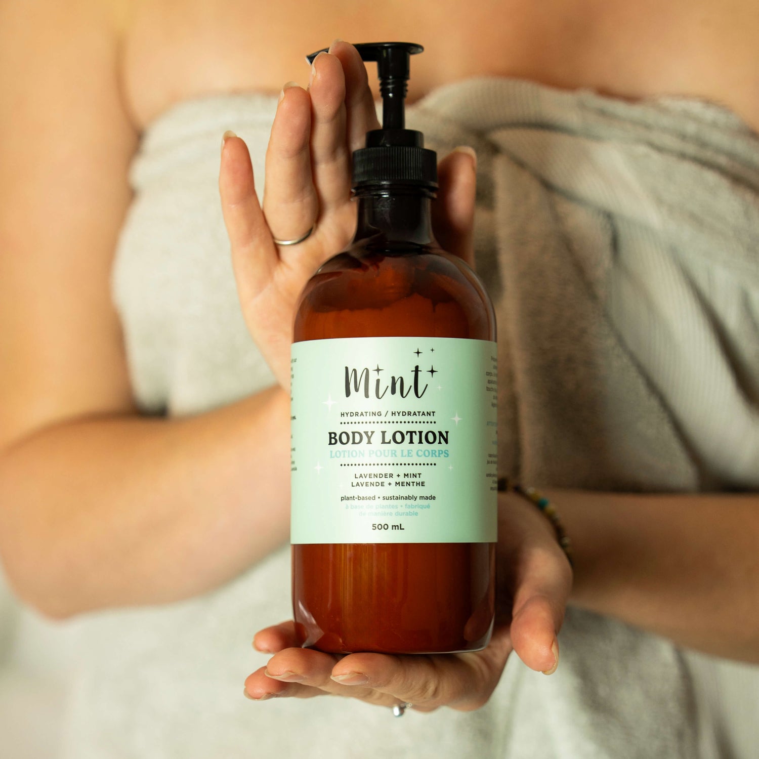 Person holding a bottle of Mint+ body lotion with a label.