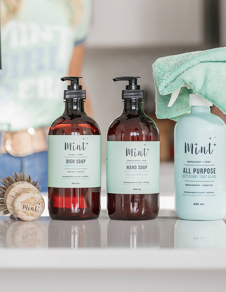 Three bottles of 'Mint' cleaning products on a kitchen counter.