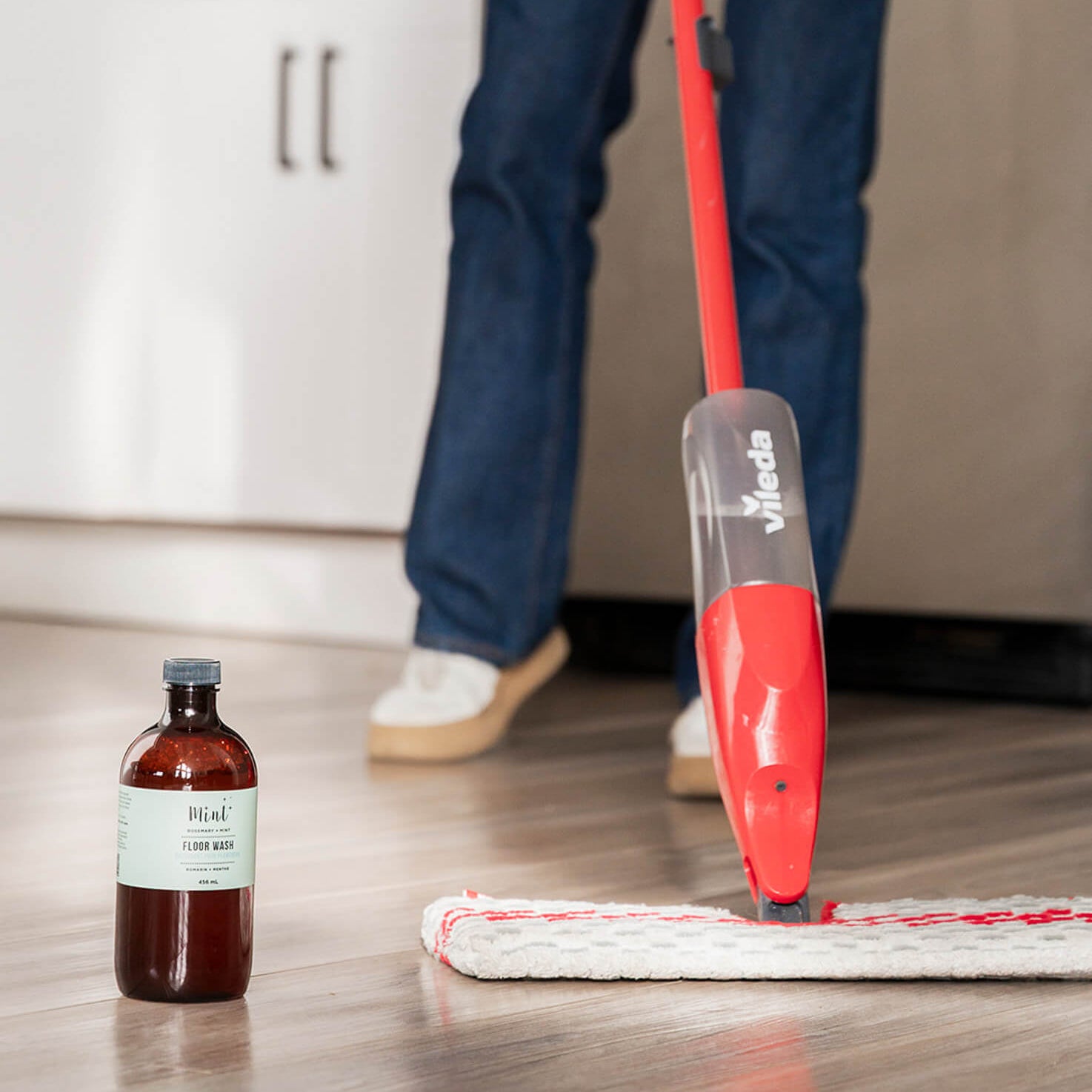 Person cleaning a floor with a red videla microfiber flat mop and a bottle of Mint Floor Wash