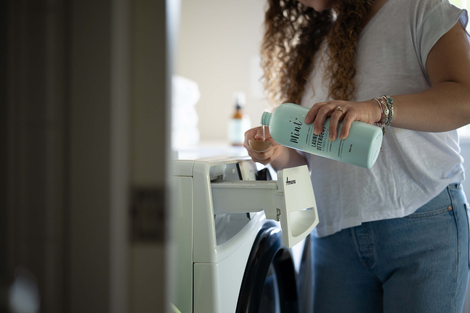Person pouring Mint Cleaning Products’ natural laundry detergent into a washing machine detergent drawer, highlighting clean ingredients and sustainable packaging.