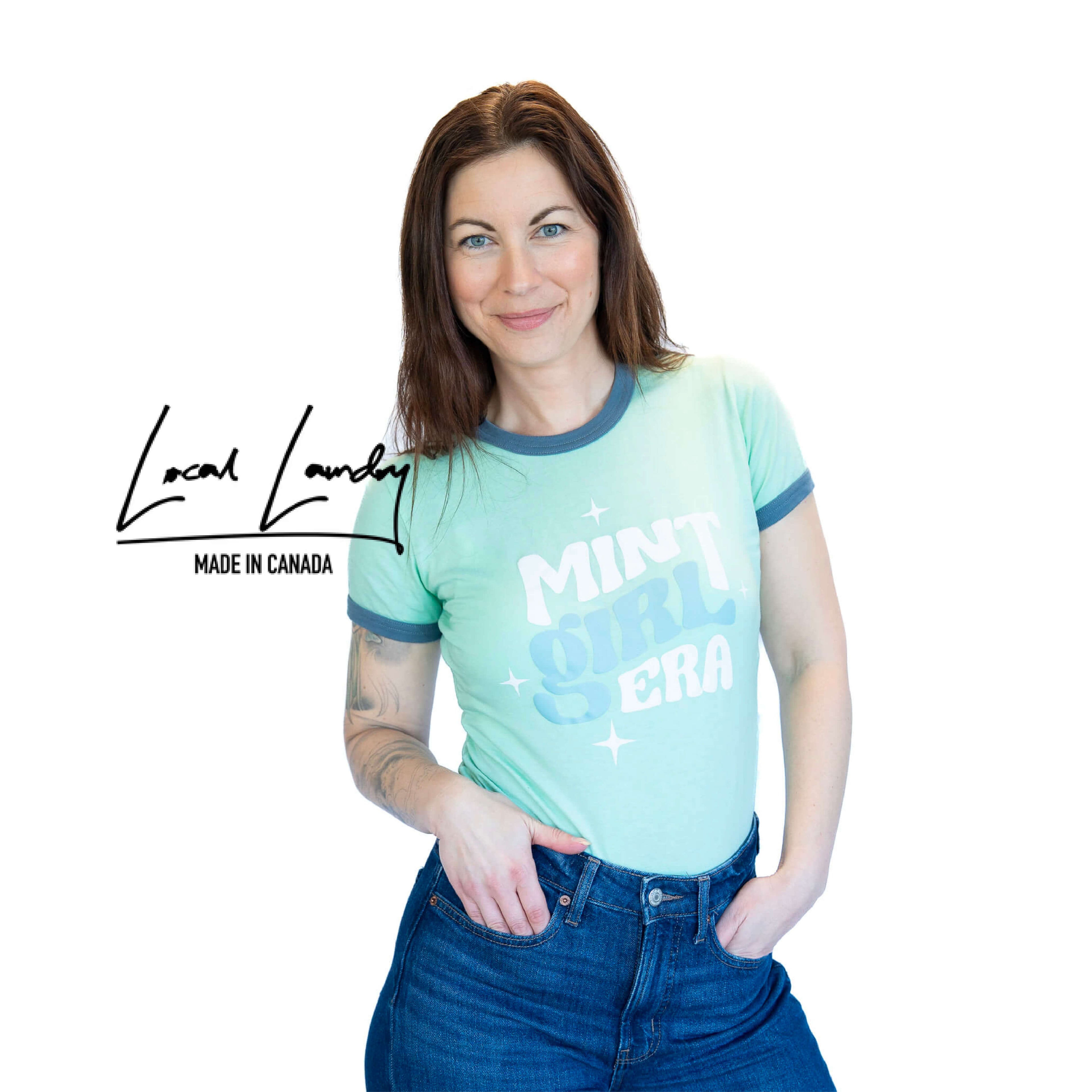 Woman wearing a light blue t-shirt with text, standing against a white background with &
