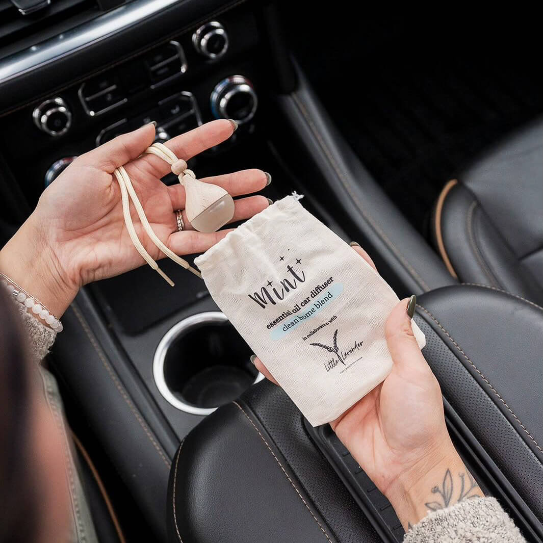 Person holding a car air freshener and packaging inside a car.