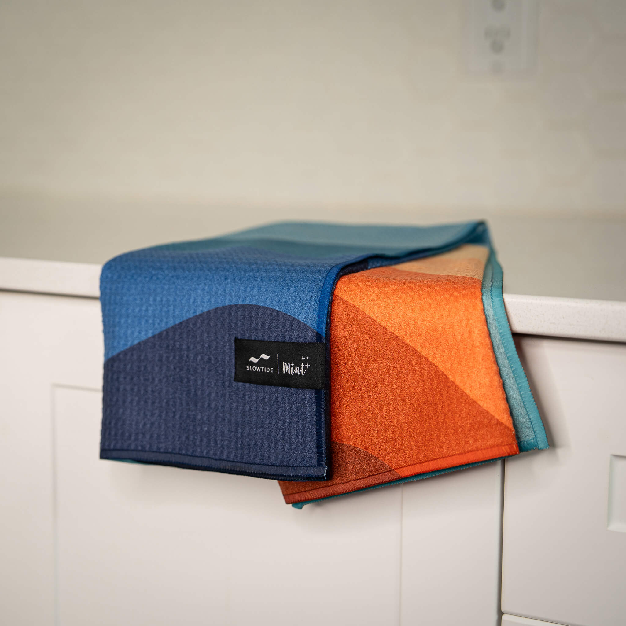 Folded towel with a brand label on a white surface.