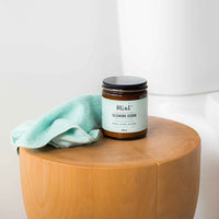 Mint Cleaning Scrub jar on a wooden stool with a microfibre cloth, ideal for versatile, eco-friendly cleaning in any room.