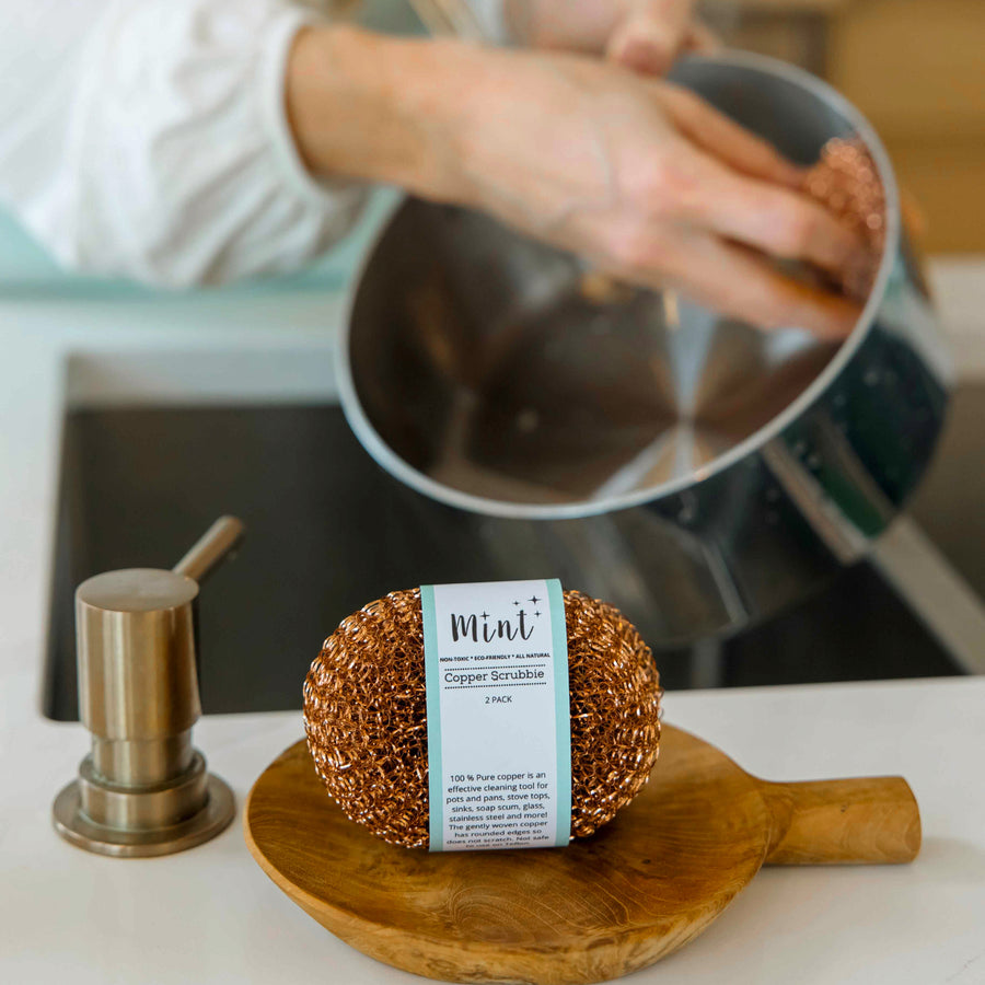 Mint copper scrubby with product label displayed on a kitchen countertop, highlighting 100% pure copper material for effective cleaning.