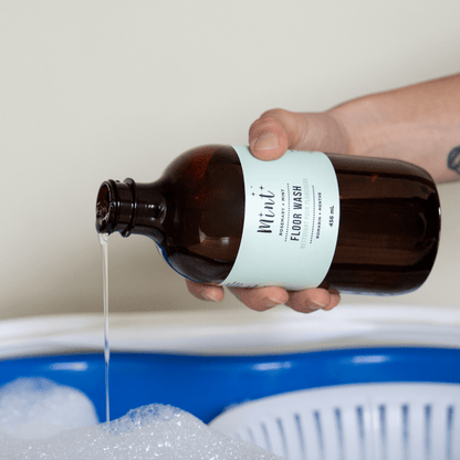 Person pouring a liquid from a brown bottle labeled &
