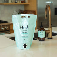 Mint 3L Dish Soap Pouch displayed on a kitchen countertop with a dispenser bottle in the background, showcasing the eco-friendly refillable design perfect for a sustainable kitchen setup.