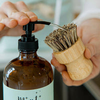 A close-up of Mint’s Dish Soap being dispensed onto a bamboo dish brush, showing an effective, eco-friendly cleaning solution.