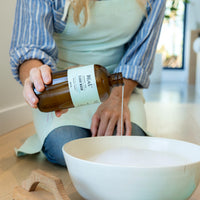 Person pouring Mint Floor Wash into a bowl with water, showcasing its natural cleaning power for floors.