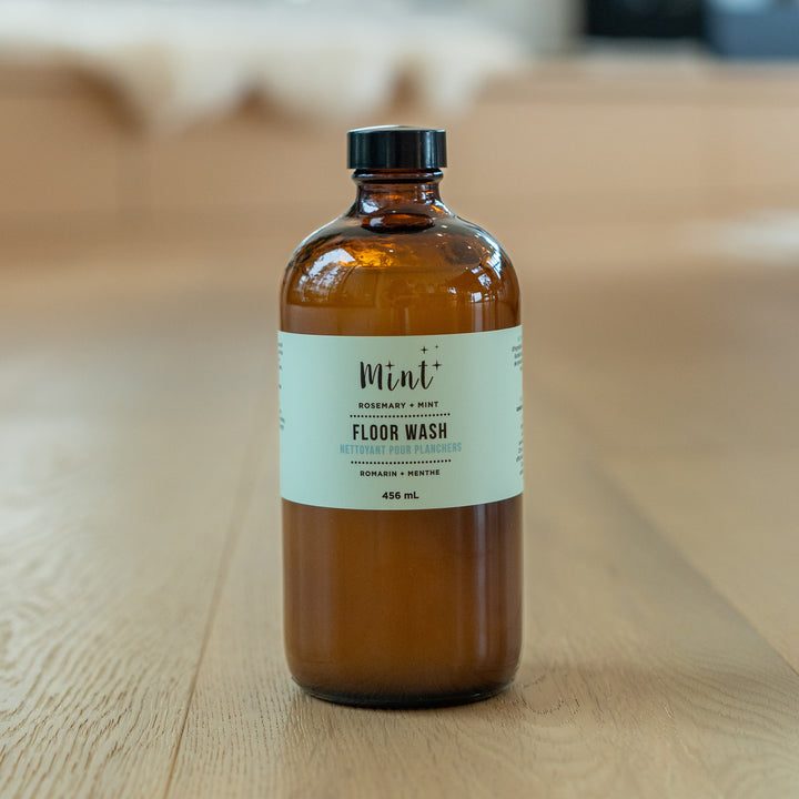 Mint Rosemary & Mint Floor Wash in a 456ml glass bottle, displayed on a wooden floor, showcasing its eco-friendly and natural cleaning formula.