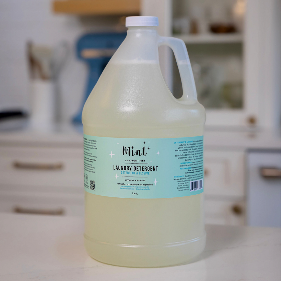 Mint Cleaning Products' 3.8L jug of Lavender + Mint Laundry Detergent, displayed in a kitchen setting. The jug features a light blue label with product information, highlighting its eco-friendly and biodegradable formula.