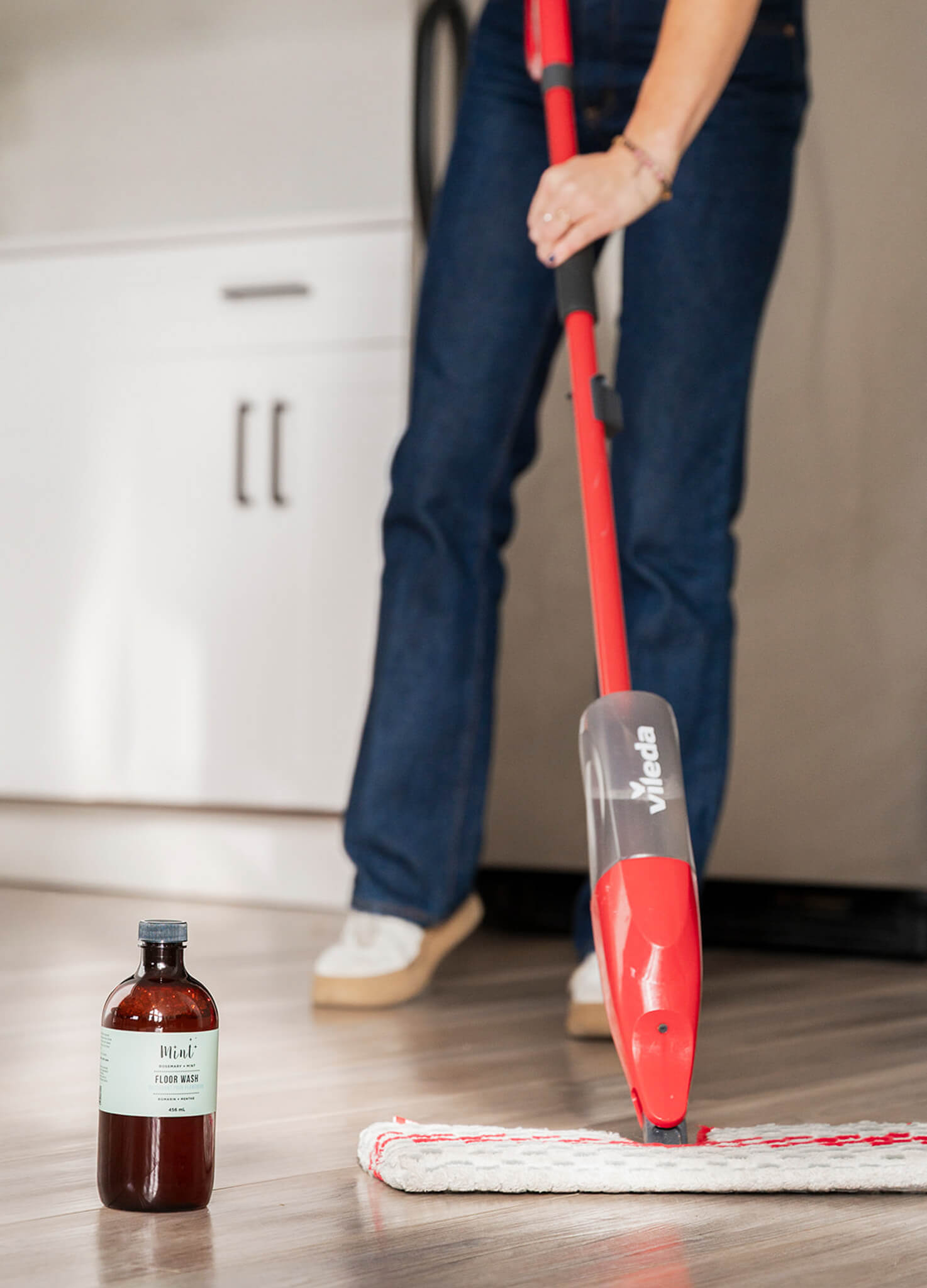 Person cleaning a floor with a red videla microfiber flat mop and a bottle of Mint Floor Wash