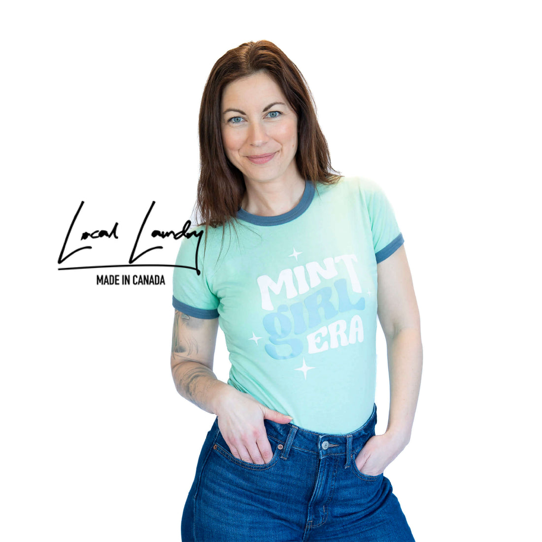 Woman wearing a light blue t-shirt with text, standing against a white background with &