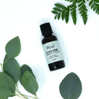 Mint Clean Home Essential Oil Blend bottle with fresh eucalyptus and fern leaves around, placed on a white background.