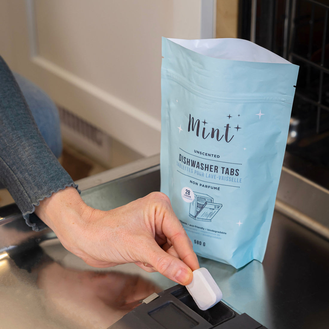 Person placing a Mint Dishwasher Tab into a dishwasher compartment, demonstrating the easy, eco-friendly solution for spotless dishes.