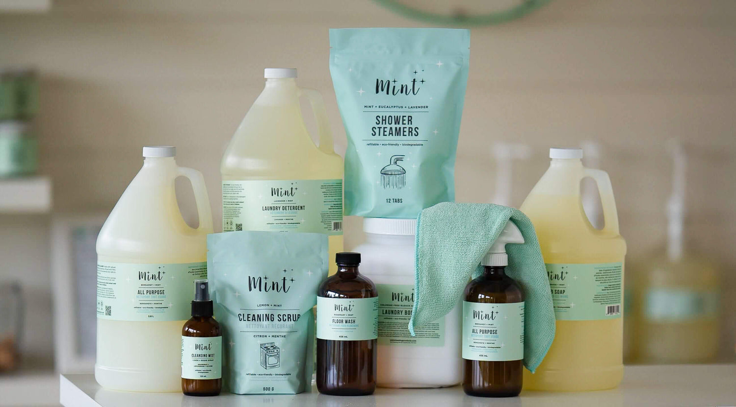 A display of Mint Cleaning Products for businesses, including eco-friendly and biodegradable all-purpose cleaner, laundry detergent, shower steamers, cleaning scrub, floor wash, and a microfibre cloth.