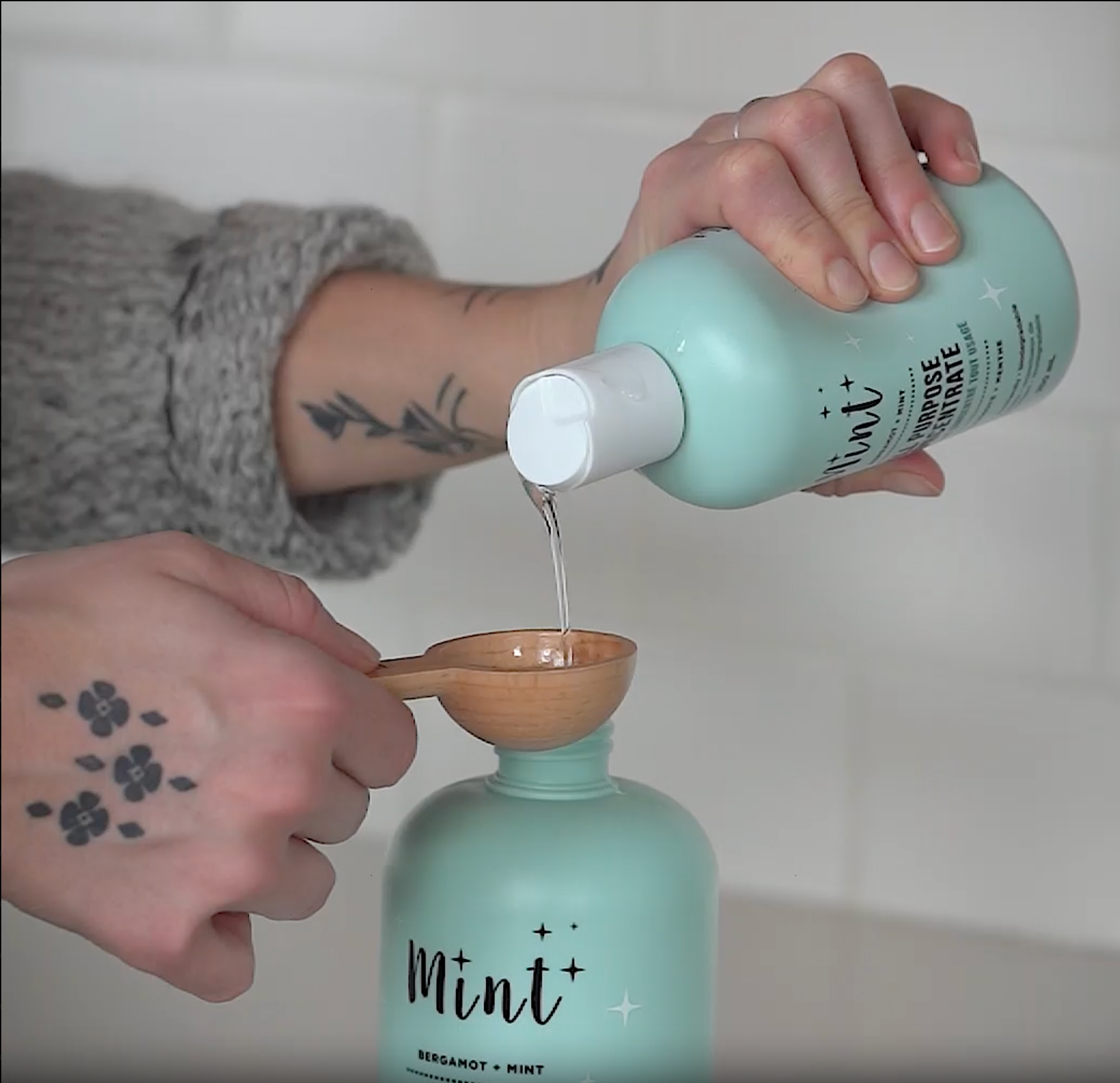 A person refills an empty all-purpose cleaner bottle using a concentrated all-purpose cleaner and water, demonstrating an easy and simple refill process