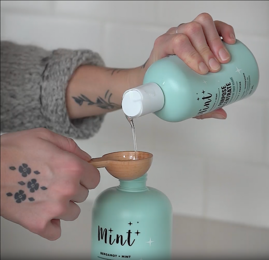 A person refills an empty all-purpose cleaner bottle using a concentrated all-purpose cleaner and water, demonstrating an easy and simple refill process