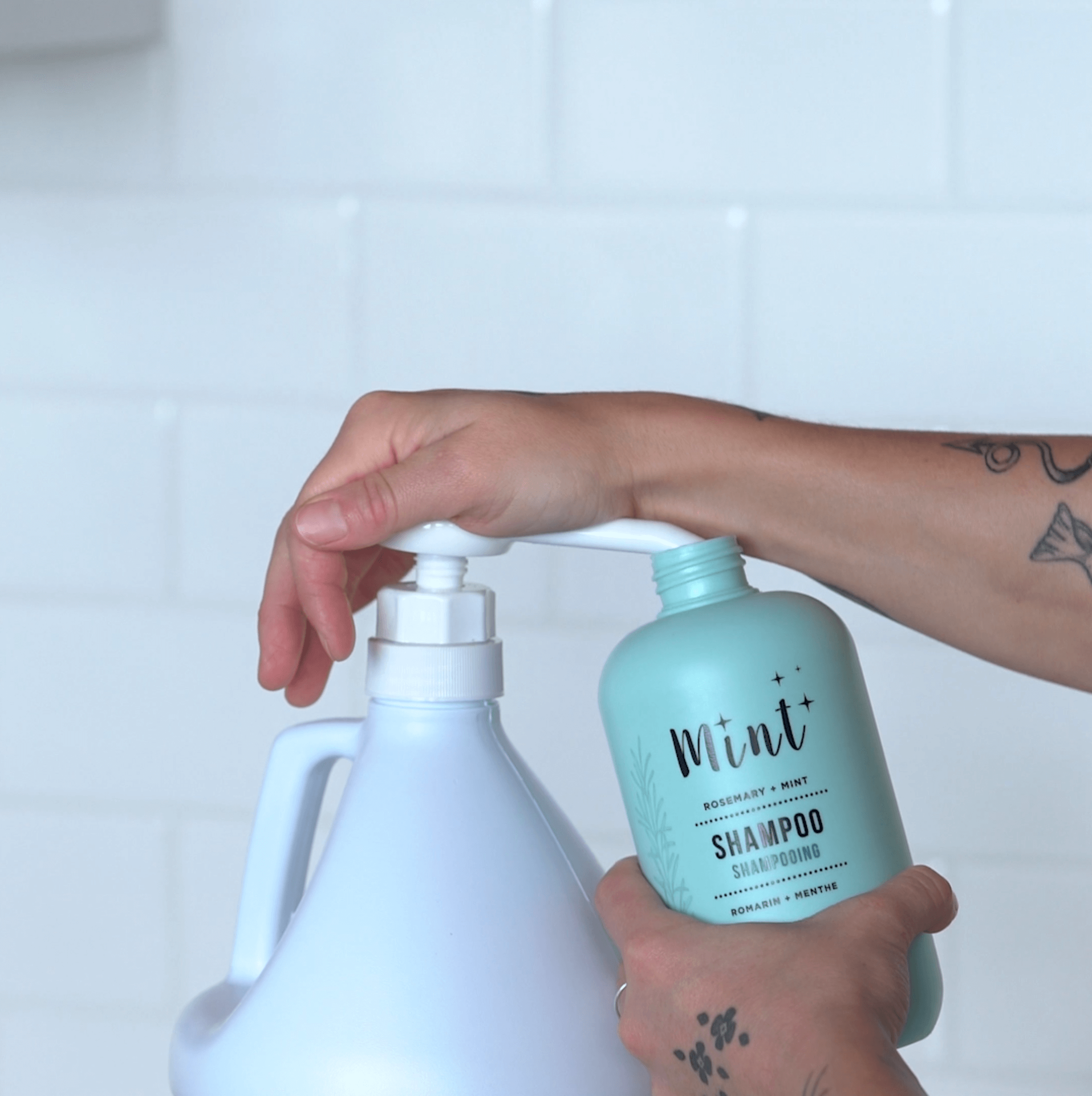 A person refills a Mint shampoo bottle using a Mint shampoo refill jug, showcasing a simple and sustainable refill process.