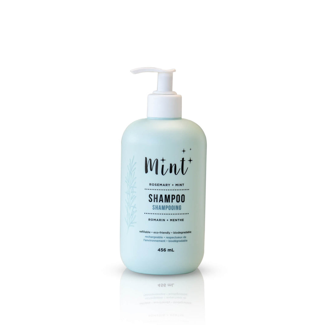 A 456 mL light blue bottle of &quot;Mint+ Shampoo&quot; with a pump dispenser. The label features the scent &quot;Rosemary + Mint&quot; and includes bilingual text, &quot;Shampooing&quot; and &quot;Romarin + Menthe.&quot; It emphasizes the eco-friendly attributes of the product, such as being refillable, biodegradable, and sustainable. The design includes a subtle botanical illustration on the left side, creating a fresh and natural aesthetic. The bottle is displayed on a clean white background.